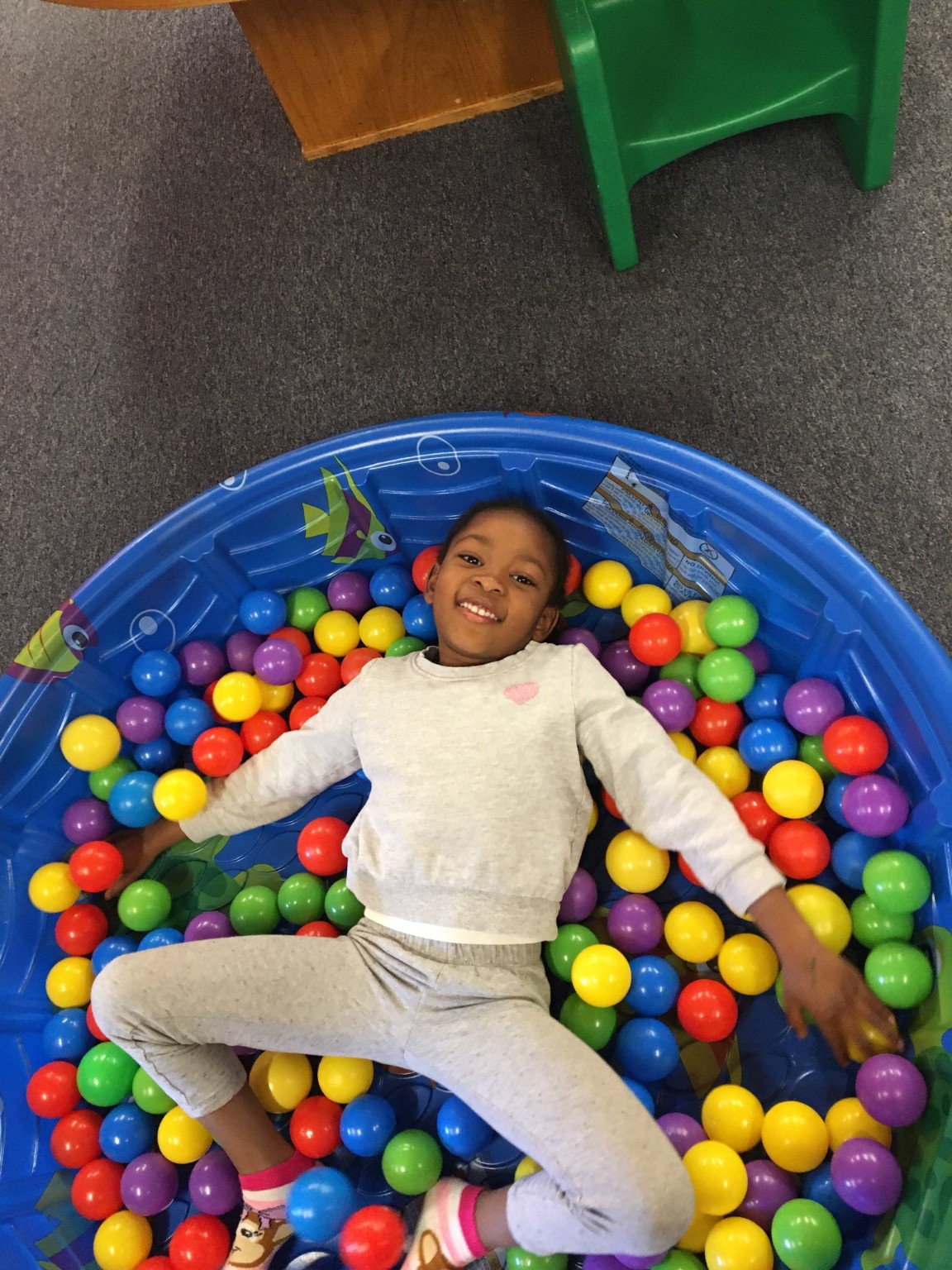 Bella smiling in a blue pool filled with colorful balls